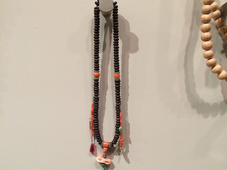 A mala of dark wooden prayer beads hanging on a wall