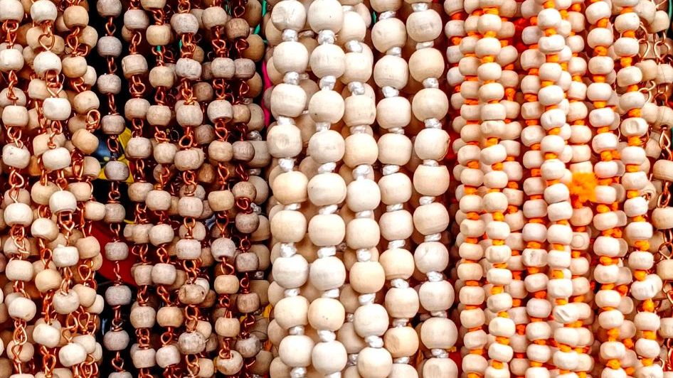 Strands of prayer bead malas hanging side by side at a temple stall